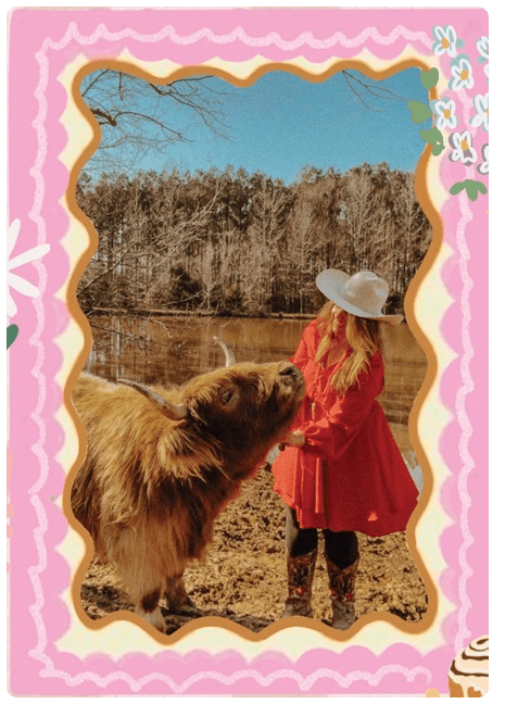 The author in a red coat with a grown-up Highland cow by the pond